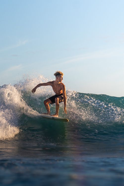 Free A skilled surfer rides a powerful wave under a clear sky, showcasing athleticism and freedom. Stock Photo
