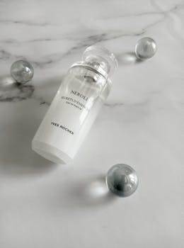 Elegant close-up of a cosmetic bottle with marble-like balls on a white background, perfect for beauty themes.