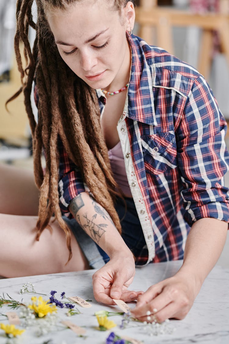 Woman In Plaid Shirt Putting A Label On A Flower