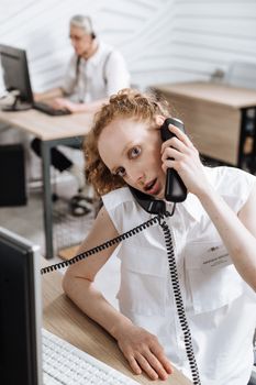 Caucasian call center agent attending calls in a modern office setting.