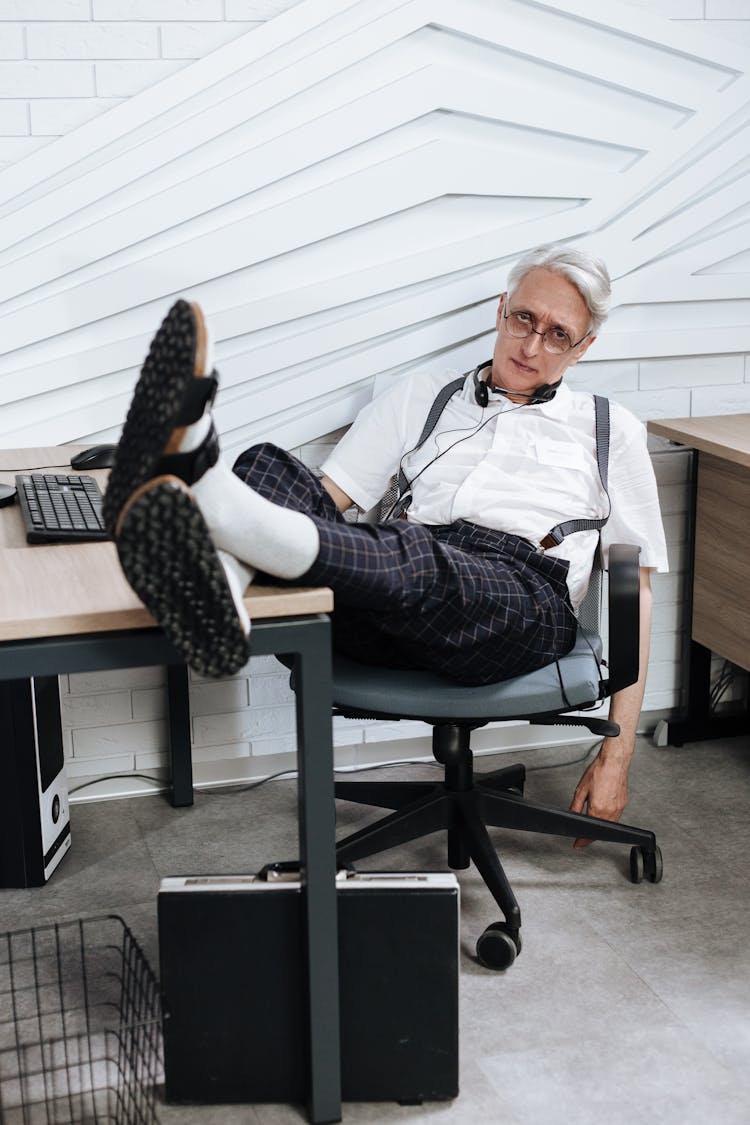 Elderly Man Sitting Om An Office Chair