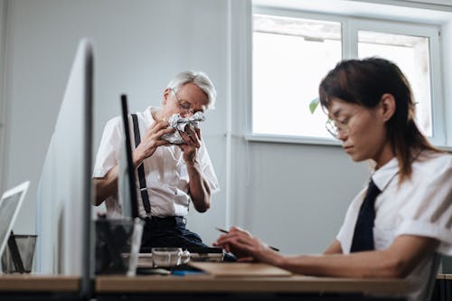 Elderly Man Eating Beside His Co Worker