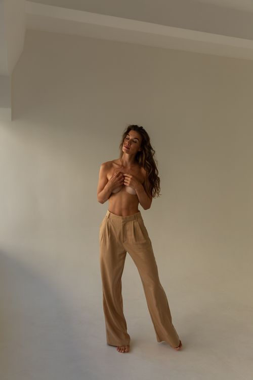 Free Emotive portrait of a woman with curly hair in a minimalist studio setting, embracing natural beauty. Stock Photo