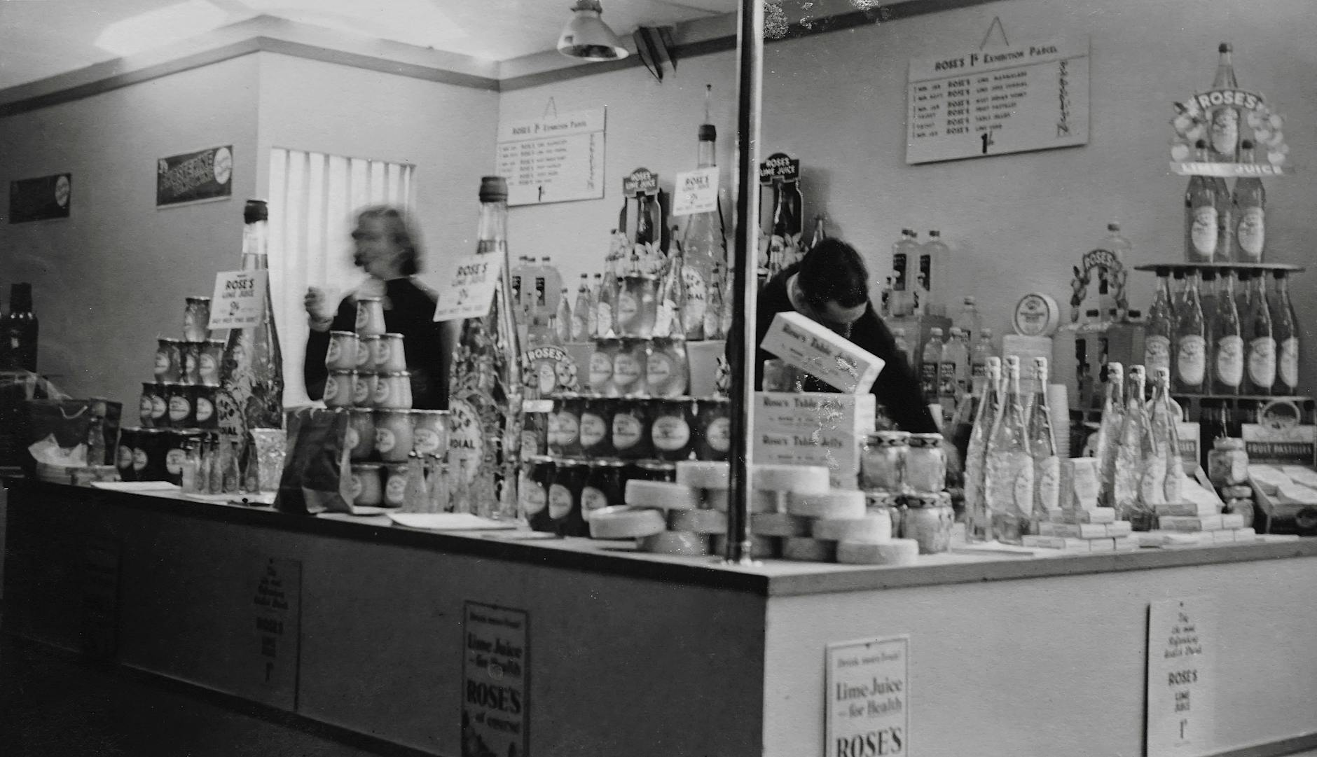 Man And Woman Standing Inside A Stall In Grayscale
