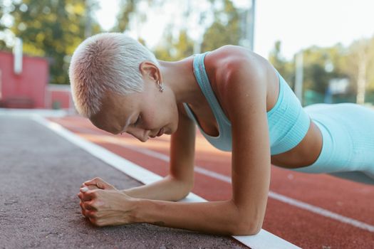 Woman planking on an outdoor track, showcasing fitness and determination.