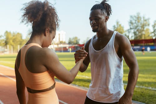 Man in White Tank Top Standing Beside Woman in Workout Clothes