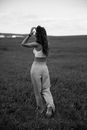 Grayscale Photo of Woman in Tank Top and Pants Standing on Grass Field