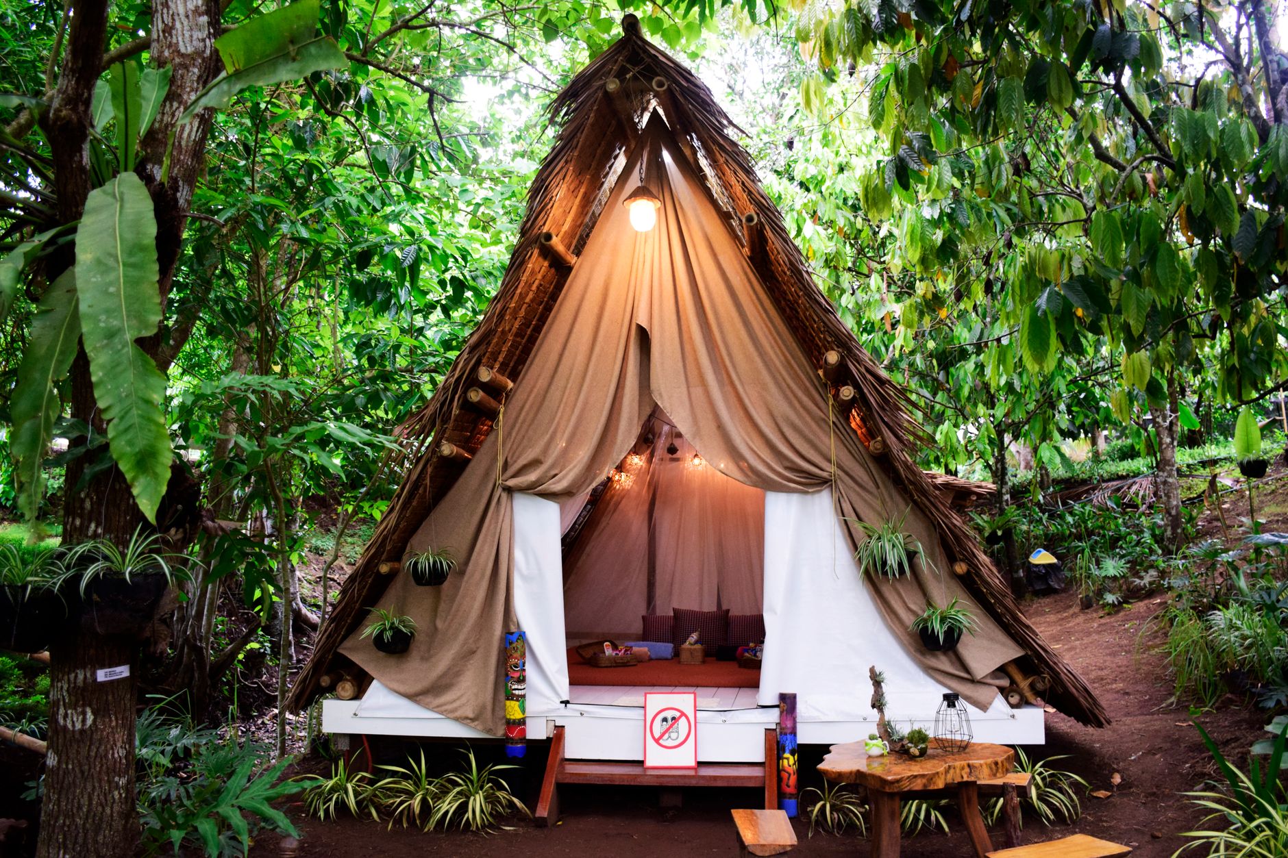 Charming A-frame tent nestled in lush forest for a unique boho camping experience.