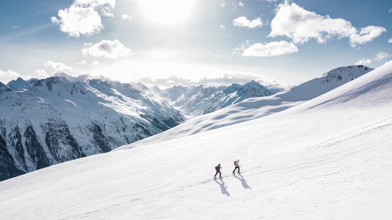 Two skiiers going up a mountain