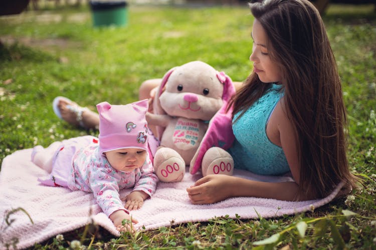 Shallow Focus Of A Mother And Her Baby On Pink Picnic Blanket