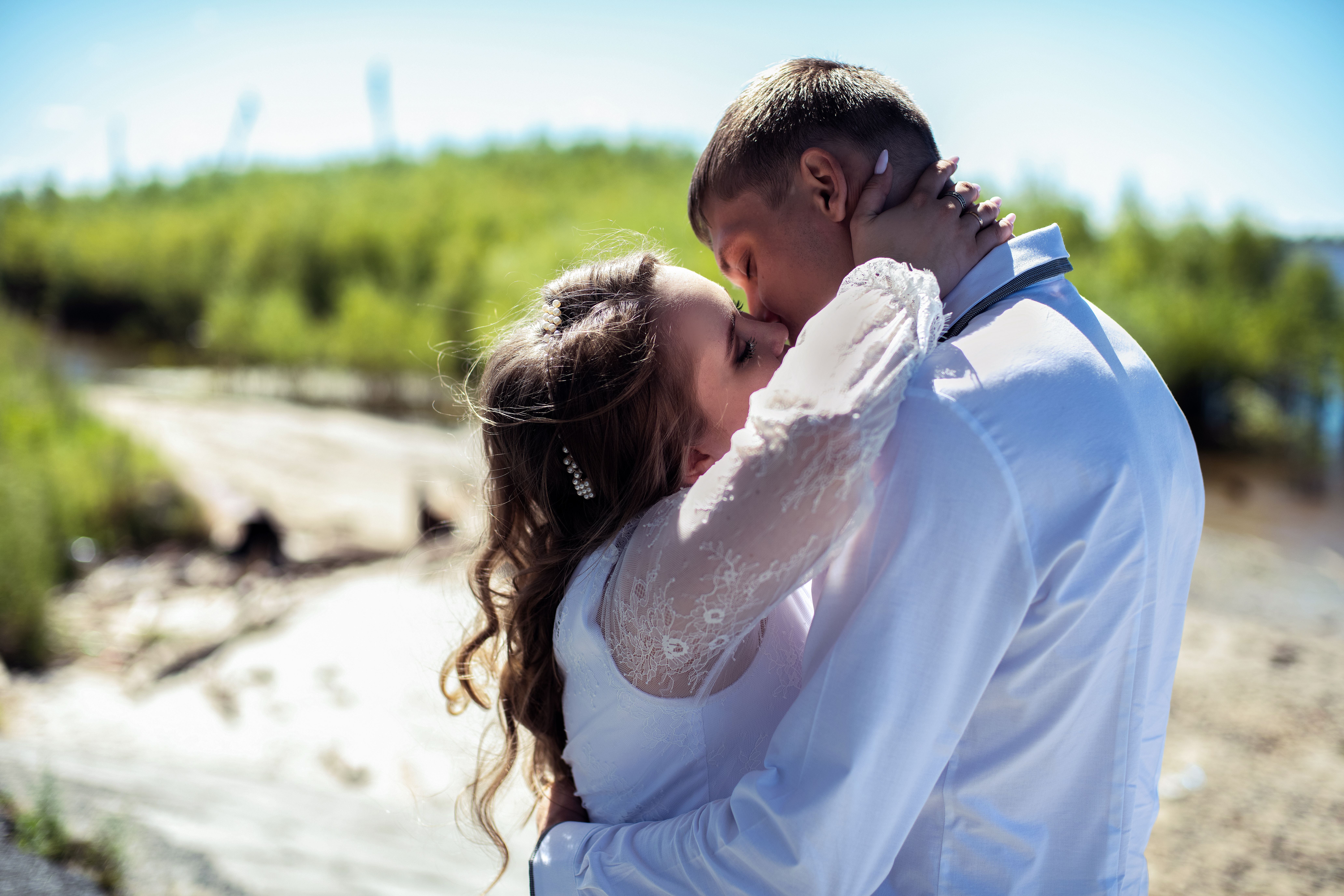 A loving embrace and kiss between a bride and groom outdoors.