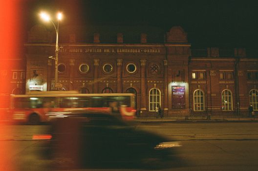 A nighttime city street with moving vehicles and historic architecture.
