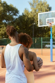 Young couple enjoying a game of basketball on an outdoor court during the day.