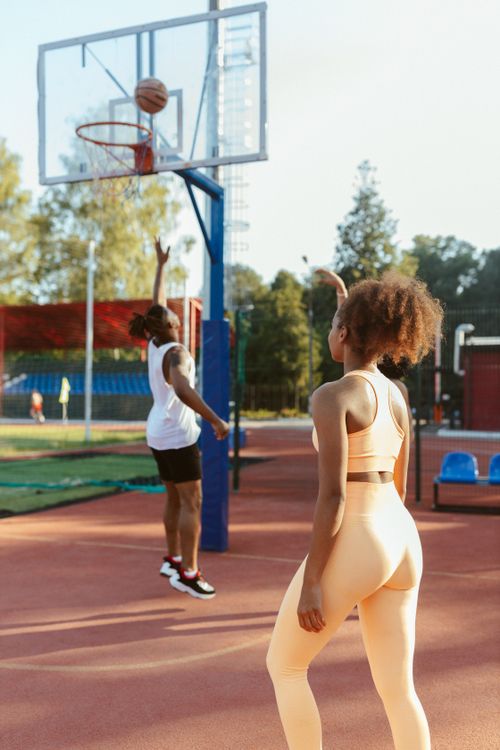 Free Two adults engaged in a leisure game of basketball on an outdoor court, showcasing dynamic sports action. Stock Photo
