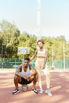 Two athletes on an outdoor basketball court ready for action.
