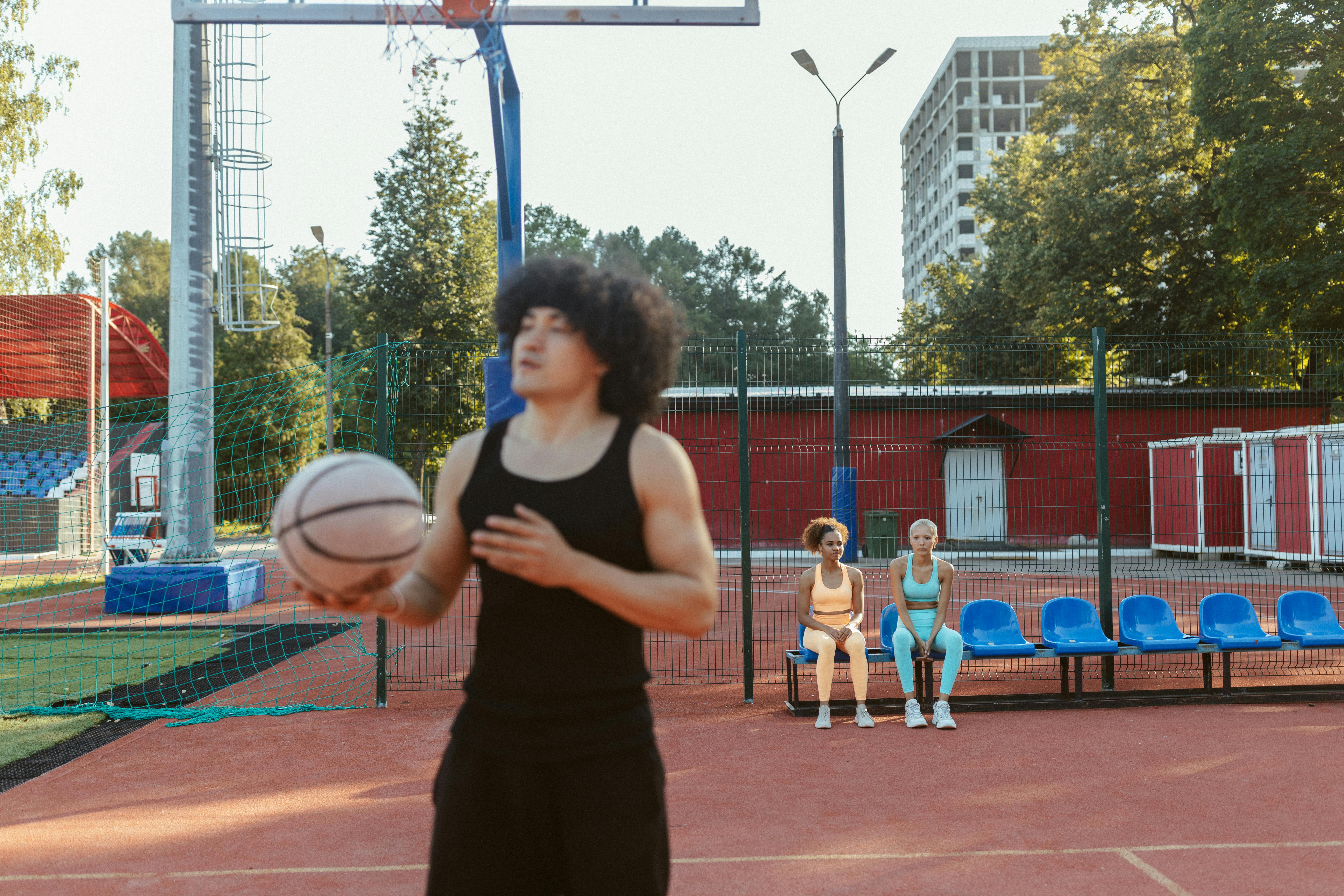 women sitting on bleachers watching a man holding basketball