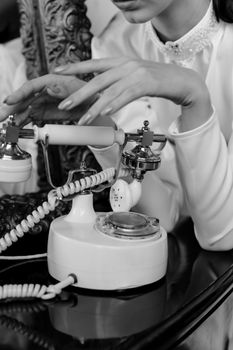 Black and white photo of a woman's hands on a vintage rotary phone, classic and timeless.
