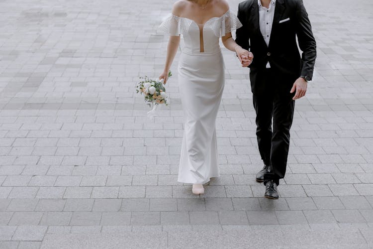 Man In Black Suit Holding Hand Of Woman In White Wedding Dress