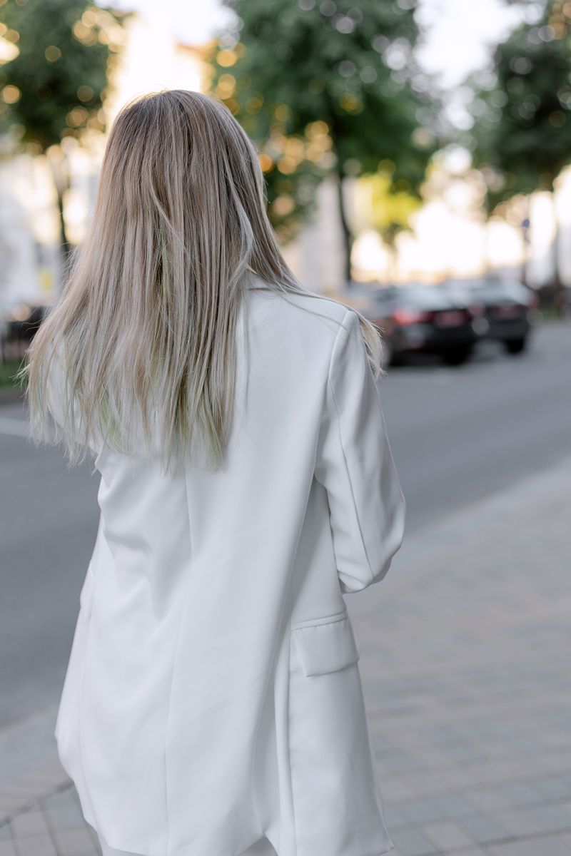 Back view of long straight silver-blonde hair and a white blazer