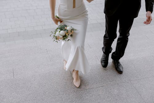 Woman in White Wedding Dress Holding Bouquet of Flowers