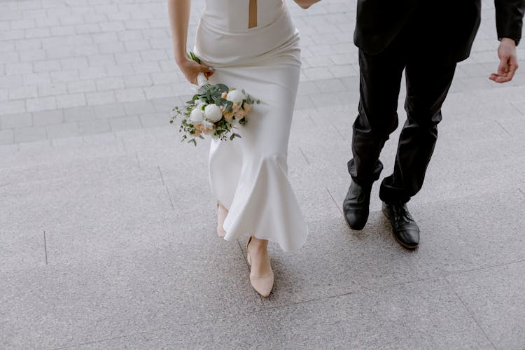 Woman In White Wedding Dress Holding Bouquet Of Flowers