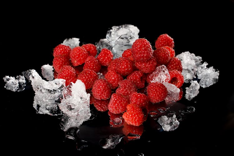 Red Raspberries With Ice On Black Surface