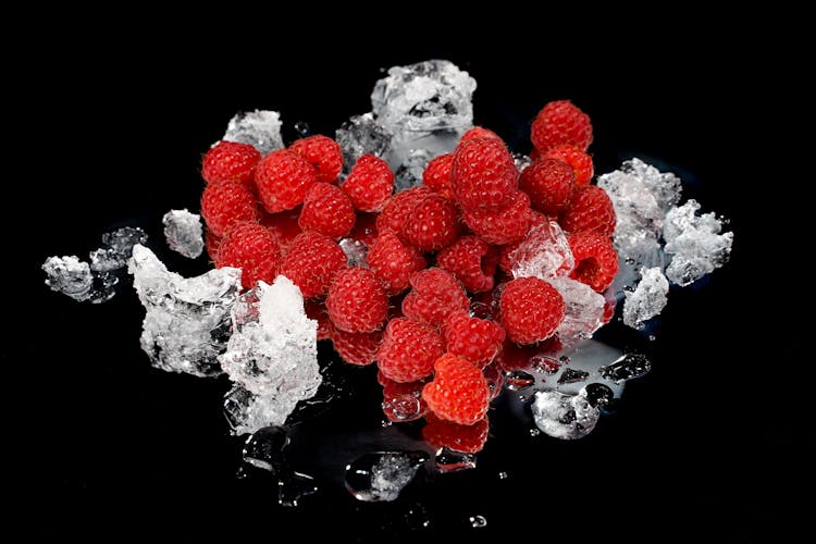 Red Raspberries With Ice On Black Surface