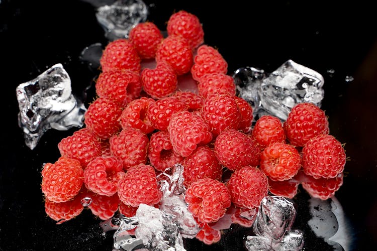 Red Raspberries With Ice On Black Surface