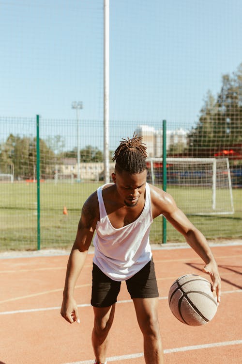 Free Woman in White Tank Top and Black Shorts Holding Basketball Stock Photo