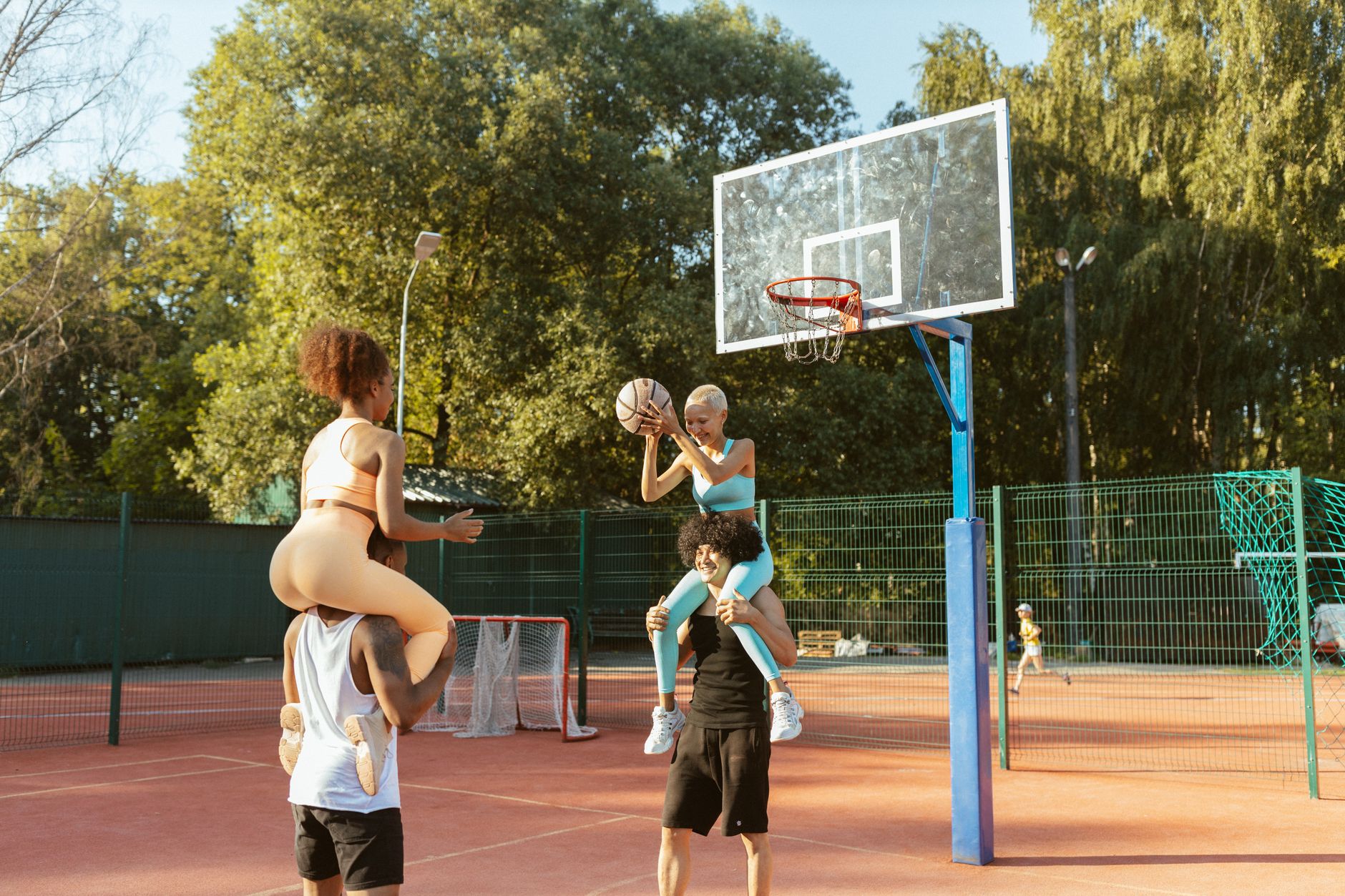 Group of young adults having fun playing basketball on an outdoor court with vibrant energy.