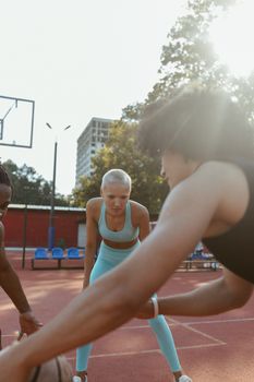 Energetic outdoor basketball game with diverse players under the sun.