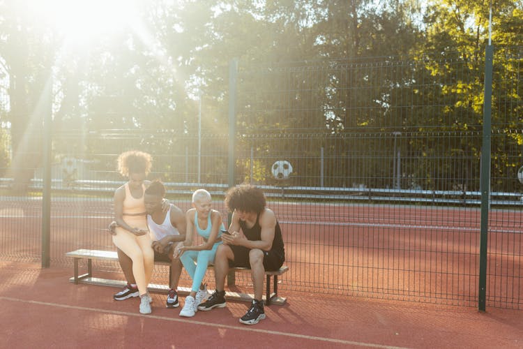 Group Of People In Sports Wear Sitting On Bench