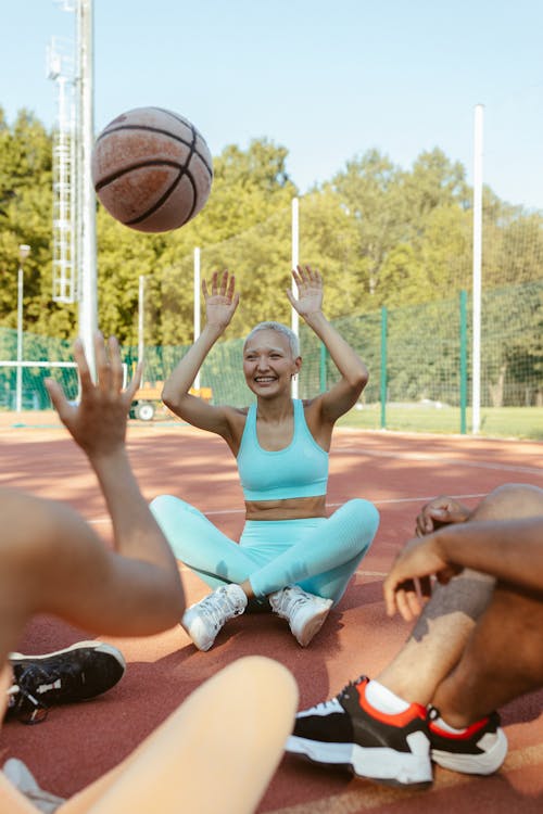 A Woman in Teal Tank Top Sitting on the Basketball Court