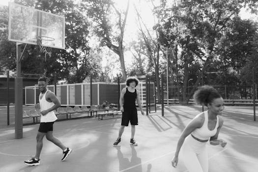 Three young adults enjoy a lively game on an outdoor basketball court.