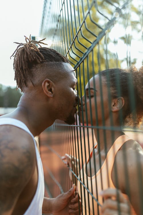 Free Man and Woman Kissing Between a Fence Stock Photo