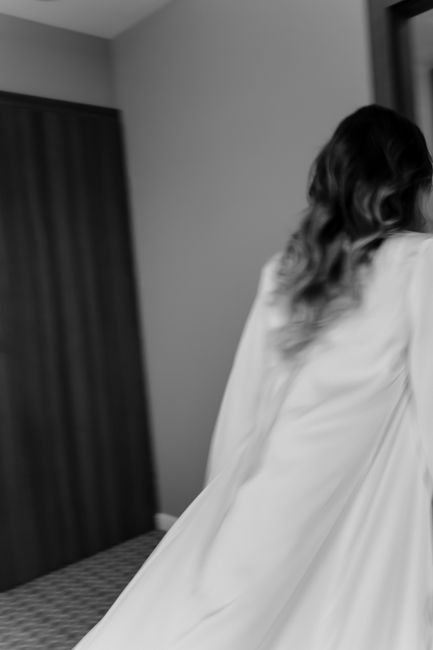 A graceful woman with curly hair in a monochrome dress captured from behind, in motion.