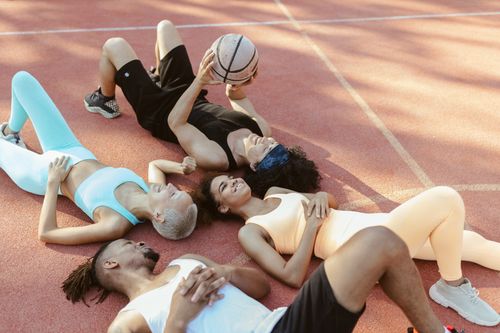 Free A diverse group of friends resting on an outdoor basketball court holding a ball. Stock Photo