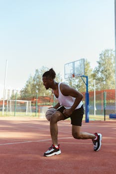 African American man dribbling a basketball on an outdoor court during the day.