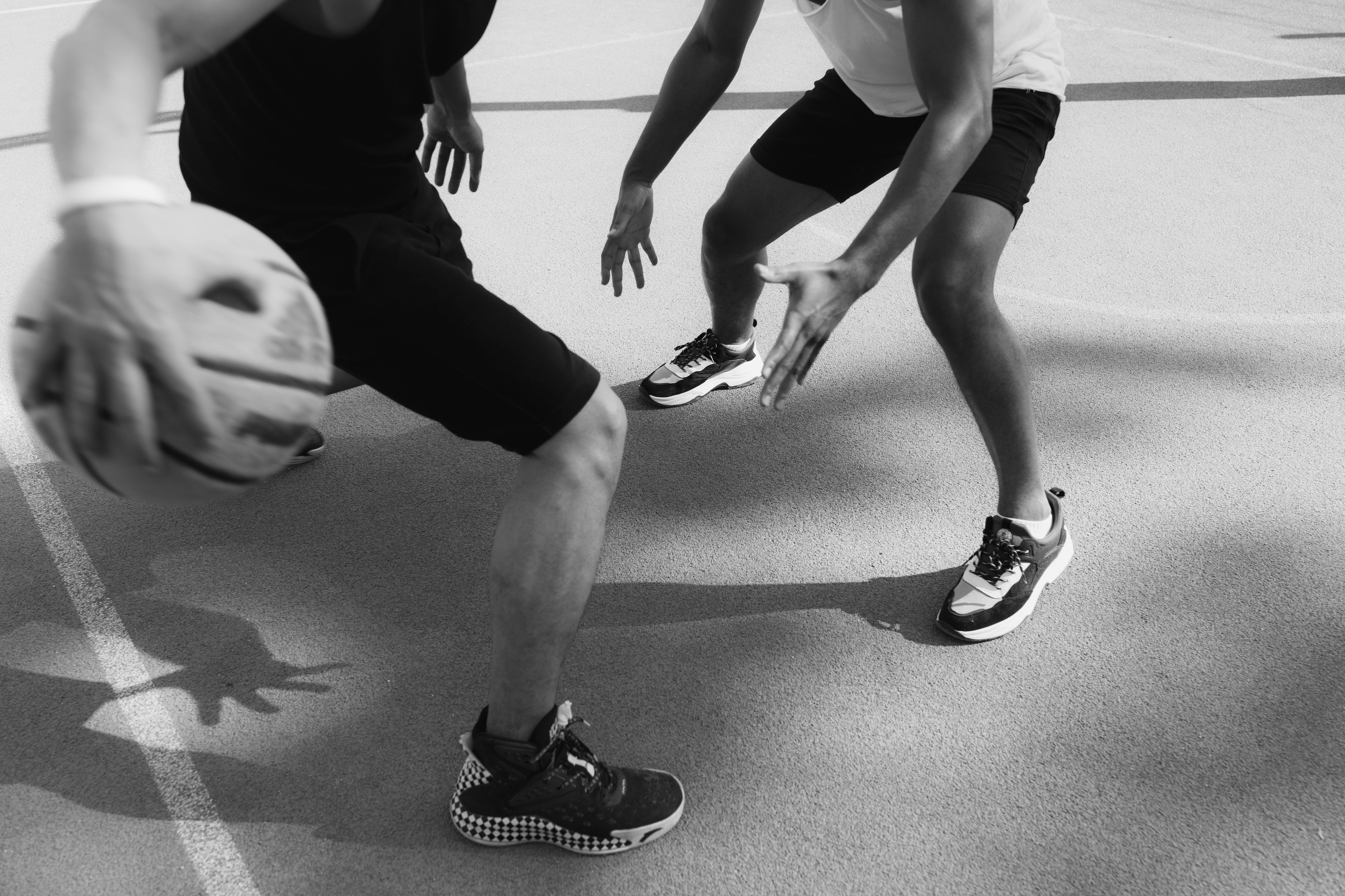 grayscale photo of two people playing basketball