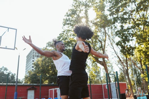 Two men playing basketball outdoors on a sunny day, displaying energy and competition.