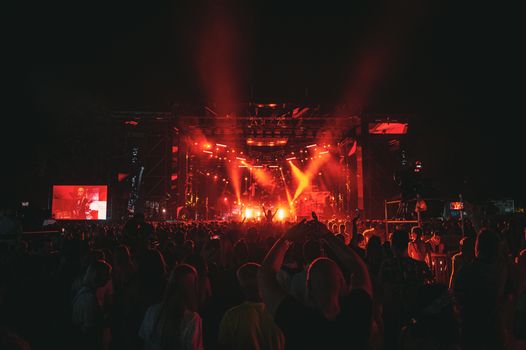 Energetic concert scene with a lively crowd and dramatic red lighting at night.