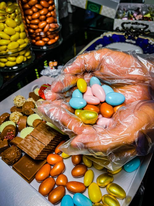 
A Person Wearing Plastic Gloves Holding Candies