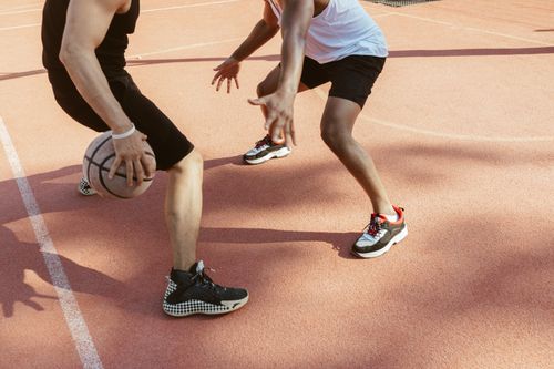 Free Two men engage in a lively basketball match on an outdoor clay court during the day. Stock Photo