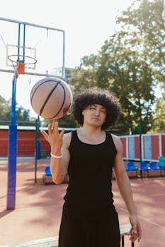 A young man with an afro wig spinning a basketball on an outdoor court. Bright, sporty, and casual atmosphere.