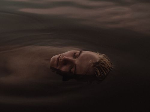 Free A serene image of a man with eyes closed floating in calm water, evoking tranquility. Stock Photo