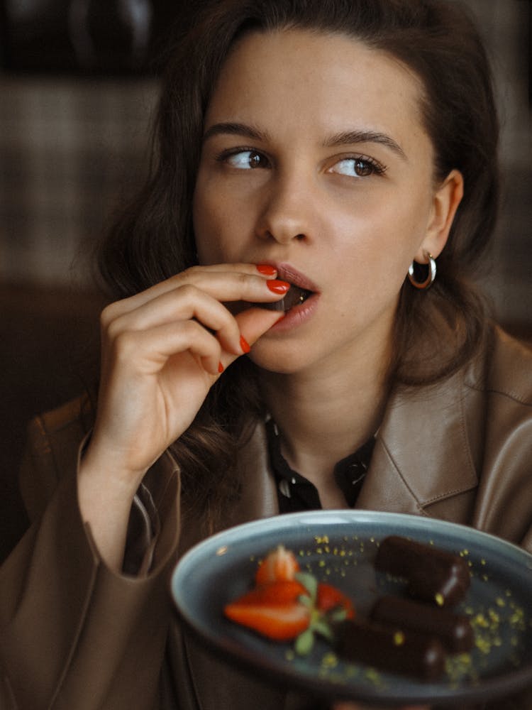 

A Woman In A Leather Jacket Eating Chocolate