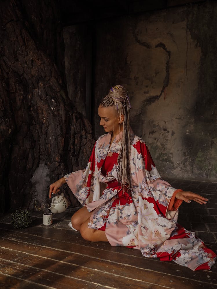 
A Woman In A Floral Robe Pouring Tea