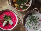 Top view of three colorful soups in rustic bowls on vintage newspaper.
