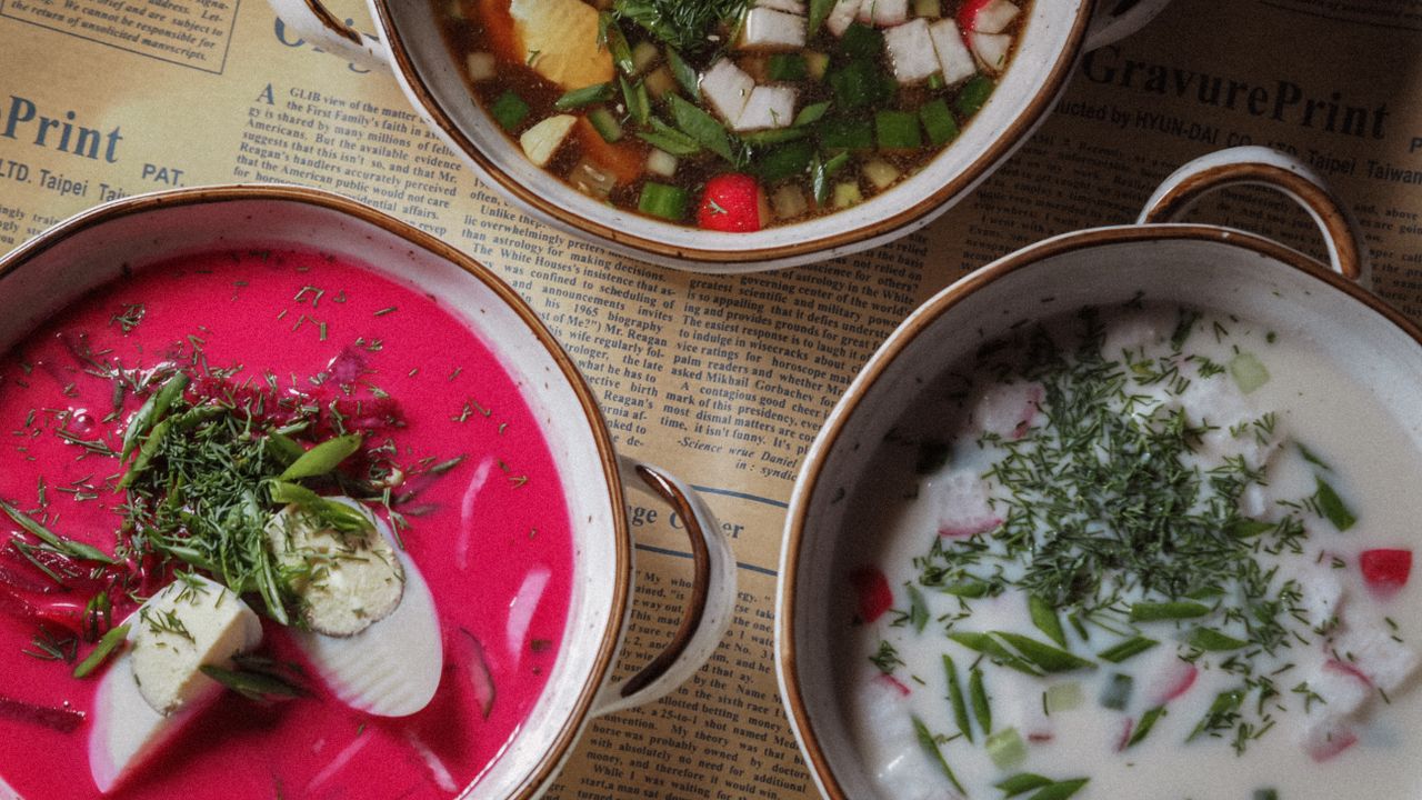 Three colorful bowls of soup photographed from above.