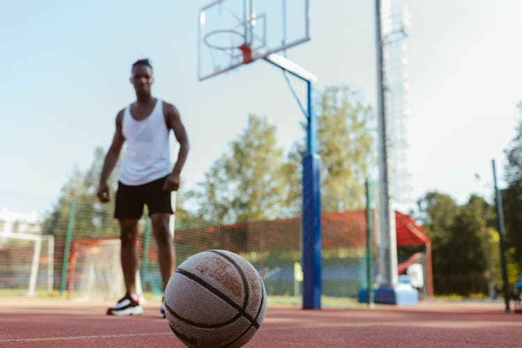 Man In White Tank Top And Black Shorts Standing On Basketball Court